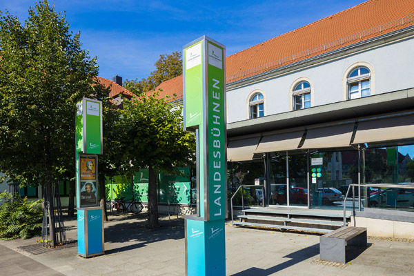 Der Eingangsbereich der Landesbühnen Sachsen in Radebeul mit Plakatsäulen - Link auf die Unterseite Abos & Theatercards