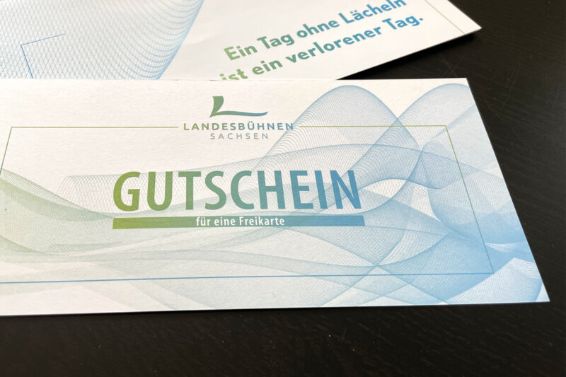 Ein Gutschein für eine Freikarte im Farbdesign der Landesbühnen Sachsen - Link auf die Unterseite Tickets & Gutscheine