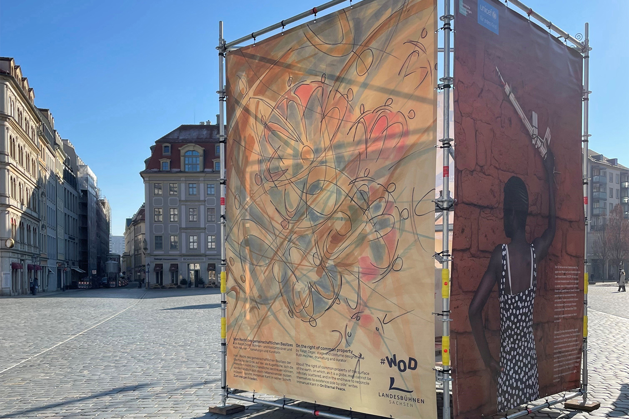 Website_WOD Auf einem kopfsteingepflasterten Platz in Dresden stehen Bauzäune mit einer Plakataktion zum Thema "Weltoffenes Dresden".